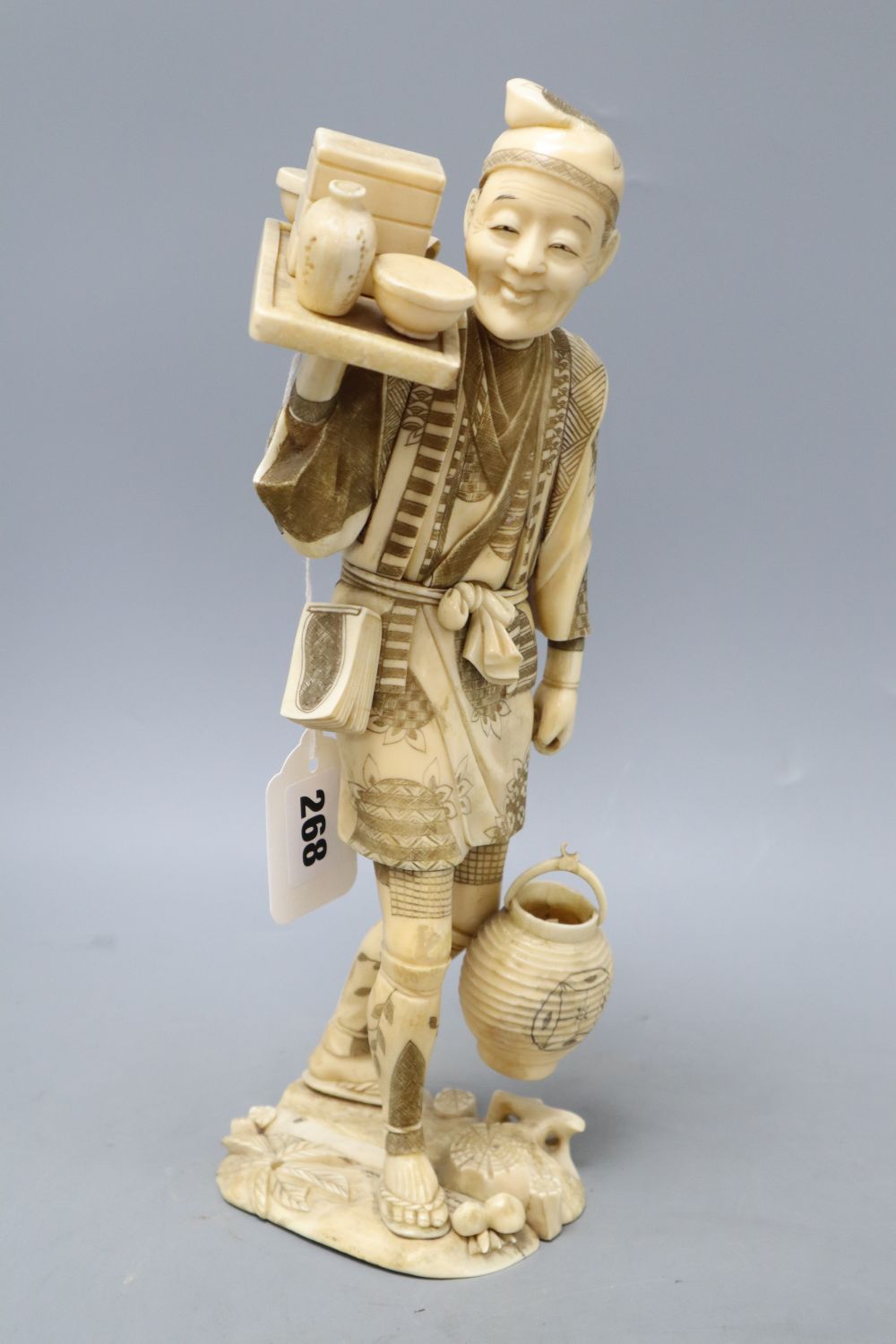 A Japanese Meiji walrus ivory figure of a tradesman, height 32cm